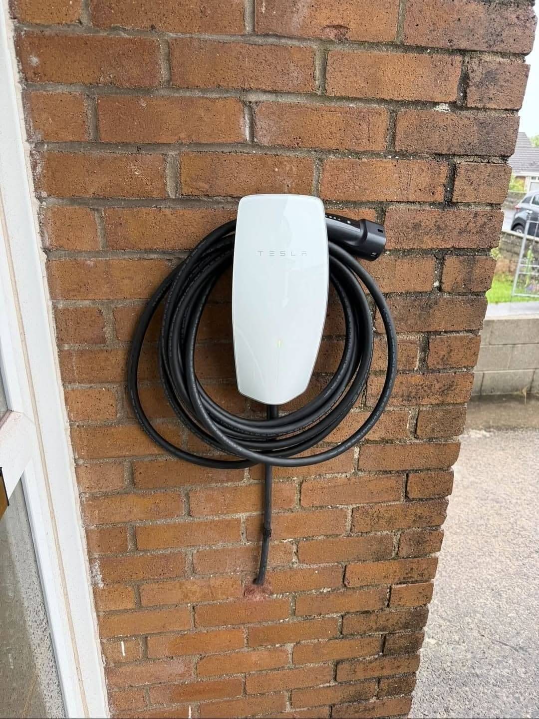 Tesla wall charger fitted by Renovolt on a brick wall