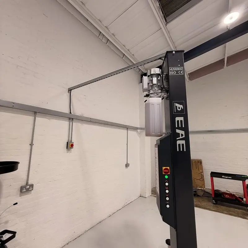 Two-post vehicle lift in a Bridgend garage workshop with its power supply run in conduit by Renovolt