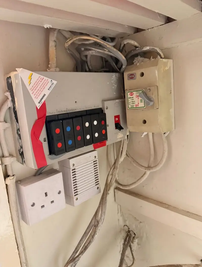 Old rewireable fuse board with taped case and a separate RCD unit in a Pencoed home, before Renovolt replaced it