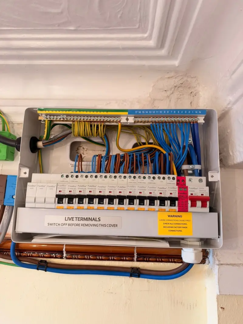 FuseBox consumer unit with twelve RCBOs, a red surge protection device and a 100A main switch, fitted by Renovolt